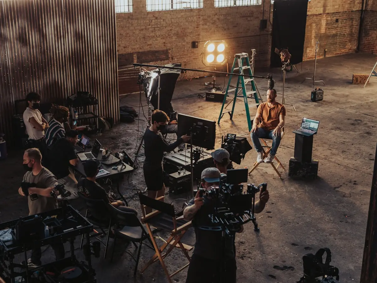 A crew set up around a camera on location, operator checking the frame.